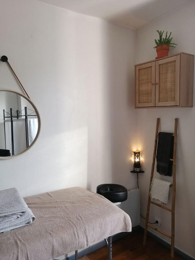 Table de massage avec échelle en bambou, meuble en rotin et miroir dans le salon de massage de Théodore Dhénain à Villeurbanne, près du métro Cusset